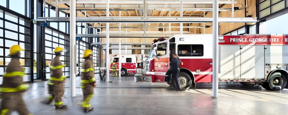 Fire truck and firefighters in uniform inside a fire hall