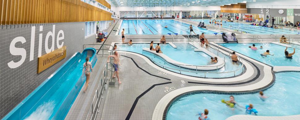 An overhead shot of the Canfor Leisure Pool with people swimming and walking on the pool deck